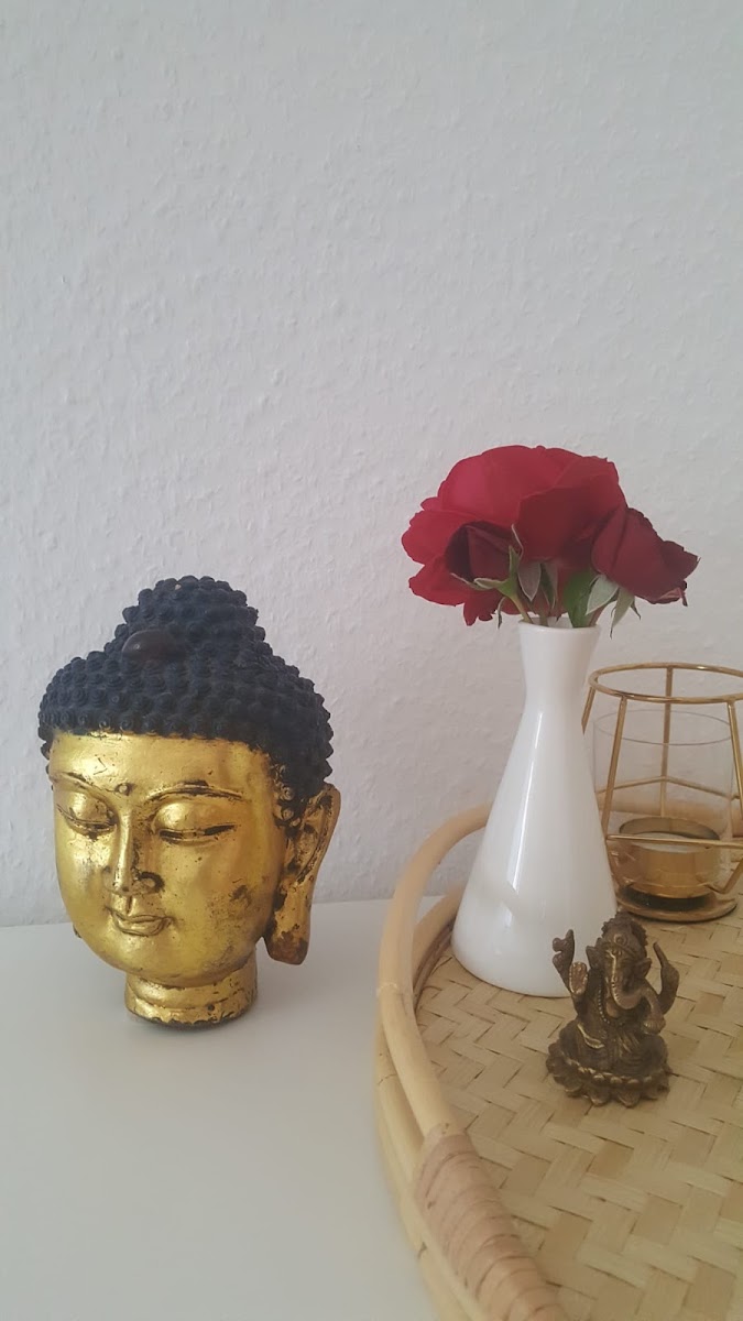Ruhige Deko-Ecke im Behandlungsraum mit Buddha-Figur und Blumen